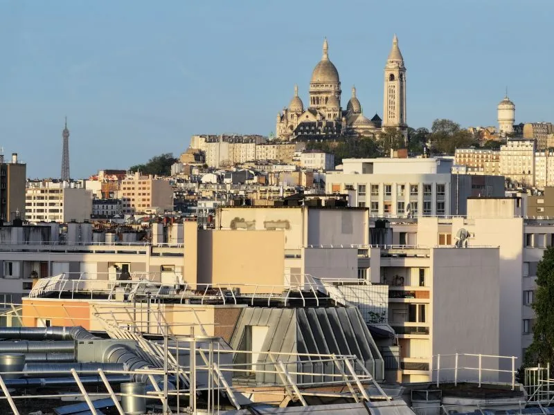 Aerial drone shot of the Paris rooftops at golden hour, with the Sacre-Coeur and the Eiffel Tower in the background — Dronexperts video production