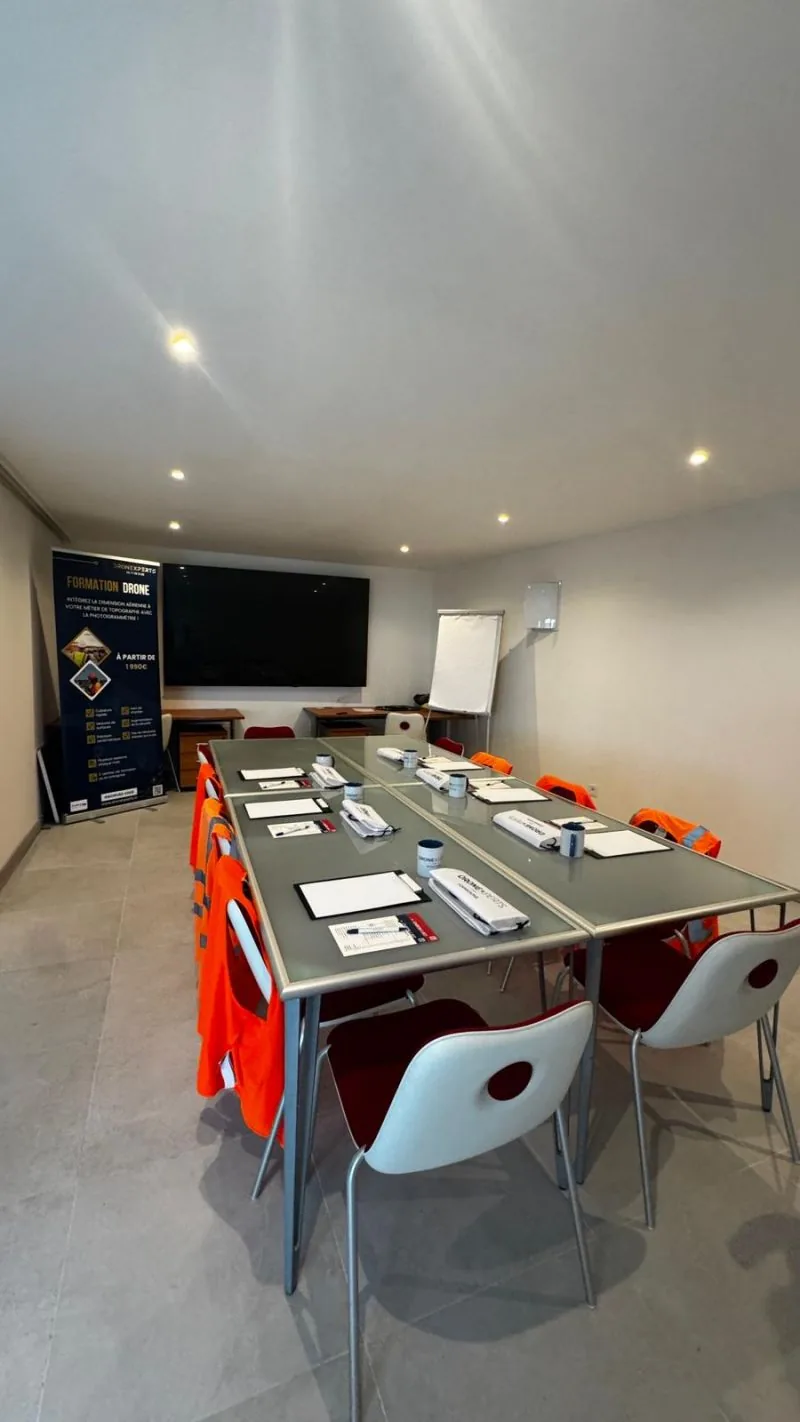 Dronexperts training room set up for drone pilot training: desks, high-visibility vests, screen and Formation Drone roll-up banner